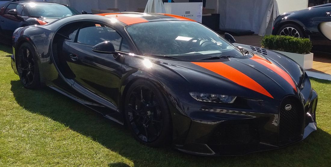 A black Bugatti Chiron Super Sport 300+ with orange stripes parked on grass