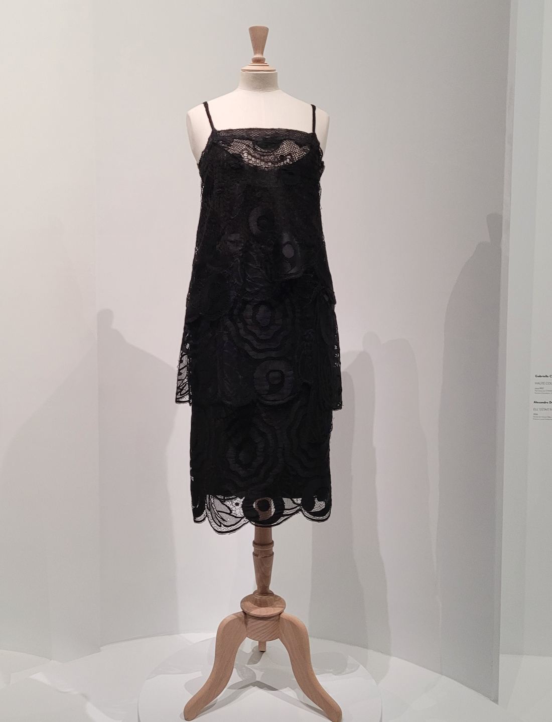 A short black lace dress by Coco Chanel on a dress form