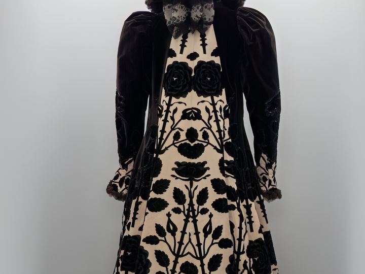 A House of Worth evening coat from about 1900 in cream satin with a bold black velvet rose pattern