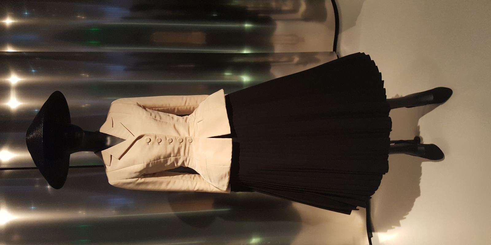 Christian Dior's Bar suit from spring 1947, with a cream fitted jacket and full black pleated skirt, at the Denver Art Museum