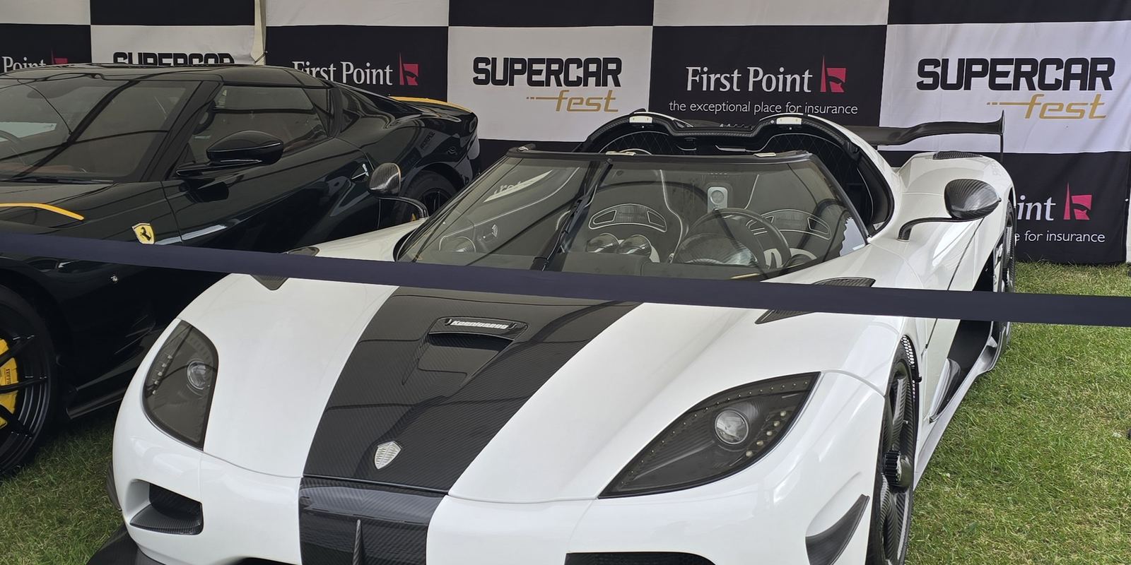 A white Koenigsegg Agera RS with a black stripe and roof scoop at a car show