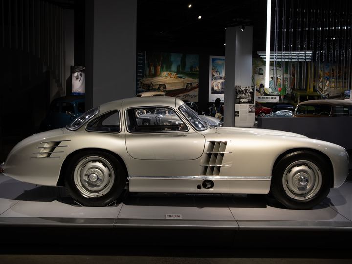 A silver Mercedes-Benz 300 SLR Uhlenhaut Coupe with gullwing doors closed, on display in a museum