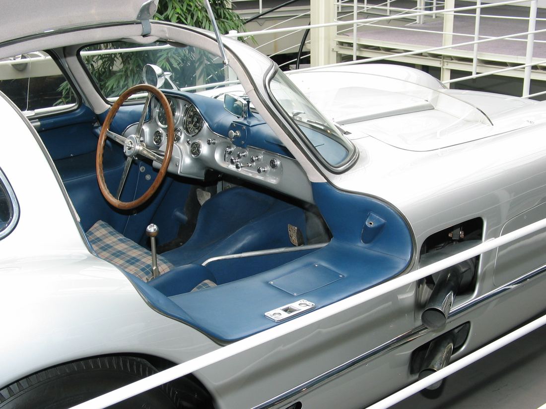 The cockpit of the 300 SLR Uhlenhaut Coupe with blue tartan seats and a large wooden steering wheel